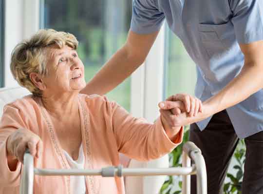 Elderly woman being helped by a nurse